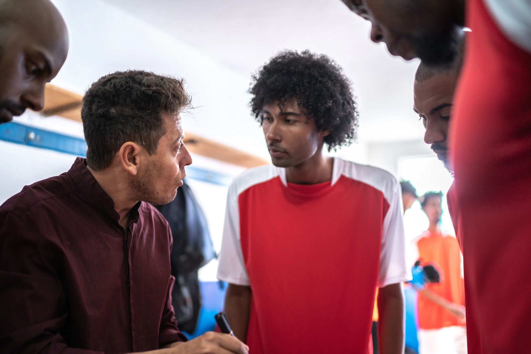 Coach speaking with athletes in a locker room about strategy
