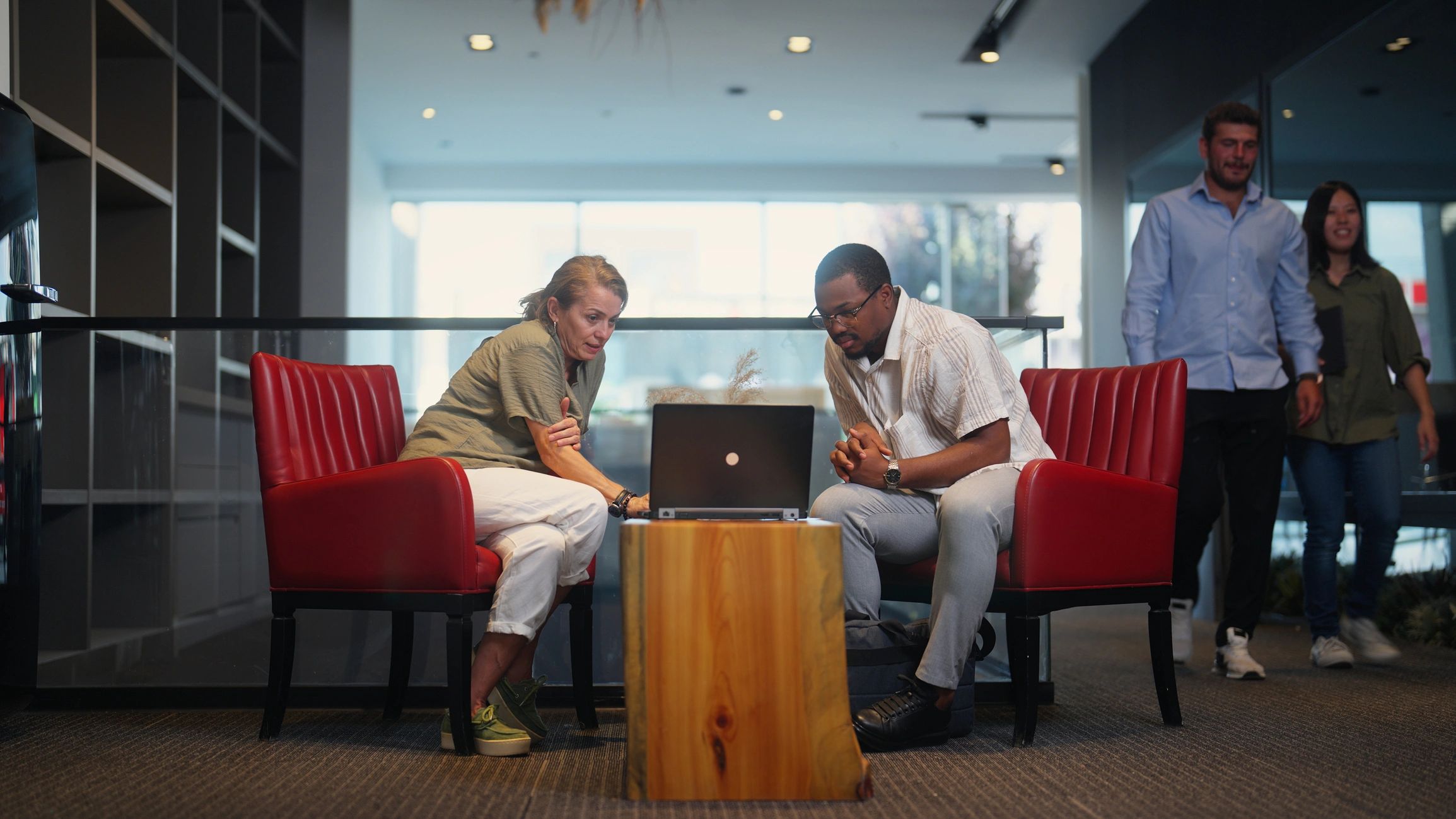 Two professionals meeting at a desk with a laptop
